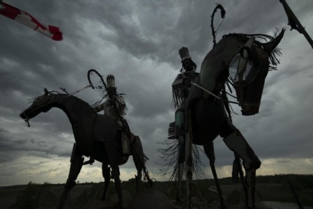 A sullen sky helped portray Jay Laber’s powerful Blackfeet warriors’ sculpture. I allowed the irony of the Canadian flag blowing amongst the Blackfeet celebration. MT, Browning. Blackfeet warriors’ sculpture (Jay Laber).